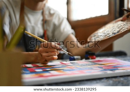 Young man artist concentrating on his painting in bright art studio. Art, education and creative hobby concept