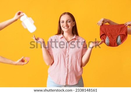Young woman and hands with menstrual things on yellow background