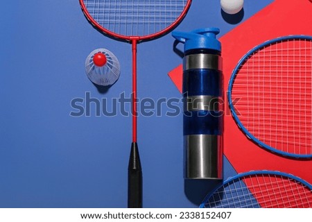 Composition with bottle of water, rackets, ball and shuttlecock on color background