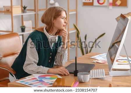Female graphic designer working with computer at table in office Royalty-Free Stock Photo #2338154707
