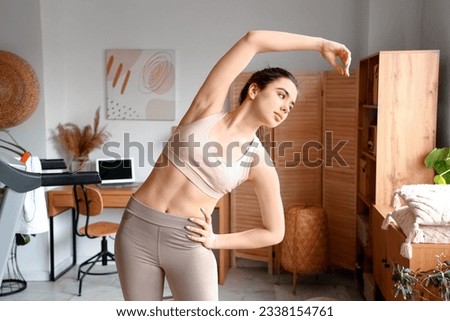 Sporty young woman training near treadmill at home