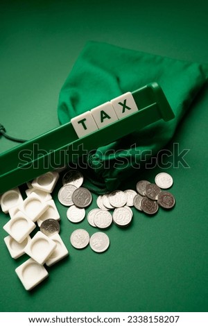Text tax on white cubes with coins on a green background. Business and tax concept. Paying taxes and planning tax deductions include strategies to minimize tax liabilities.