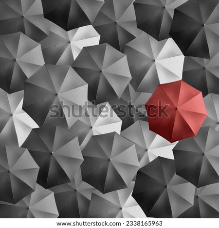 Highlighted red umbrella among multiple colourful umbrellas forming a beautiful texture pattern background symbolising rainy or summer season or a group of people.