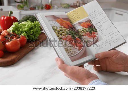 Man with recipe book at white marble table in kitchen, closeup Royalty-Free Stock Photo #2338199223
