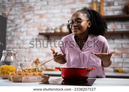 Young woman in kitchen. Beautiful African woman cooking pasta.	