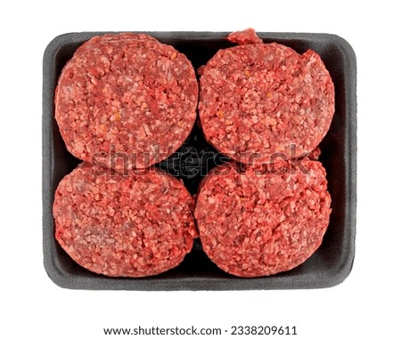 Top view of a group of four hamburger patties on a black tray isolated on a white background.