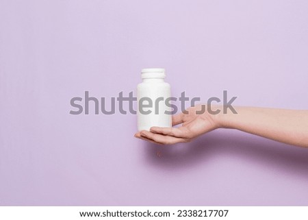 A White plastic bottle in female hand. Packaging for pills, capsules or supplements. Royalty-Free Stock Photo #2338217707