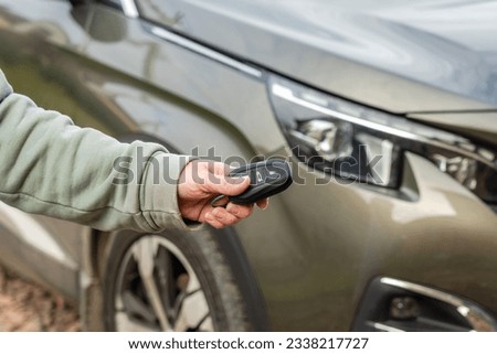 A Person with a car key in the hand stands front car. Insurance, loan and buying car concept