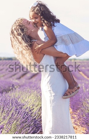 Young mother with her daughter in her arms, the mother gives a loving kiss to her daughter, in a beautiful lavender field environment. High quality photo