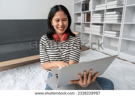 Cute teen woman asian is doing using laptop at home on the floor. She is excited and smiling