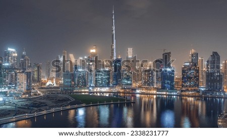 Aerial view to Dubai Business Bay and Downtown during all night with the various skyscrapers and towers along waterfront on canal night timelapse. Construction site with cranes