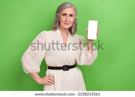 Photo of shiny cheerful woman dressed beige outfit holding apple samsung iphone device empty space isolated green color background