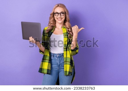 Photo of young blonde girl point finger empty space hold netbook look mockup college education remote isolated on violet color background