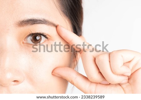 Beauty asian woman touching her healthy eyes over white background. Optimal eyes health care concept. Close up. Royalty-Free Stock Photo #2338239589