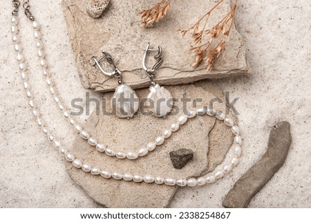 Beautiful Pearl Jewelry on white stones and sand. Necklace and earrings made of silver