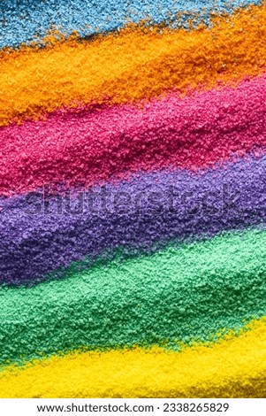 Close up of stripes of rainbow coloured sand and copy space background. Sand, texture, movement, shape and colour concept.