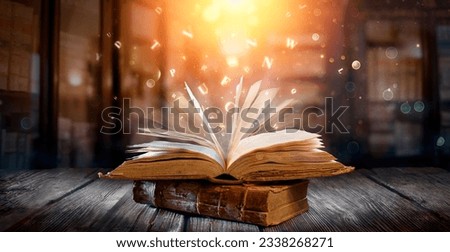 Old Book With Magic Lights And Bright Letters On Aged Table In Defocused Library Royalty-Free Stock Photo #2338268271