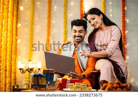 Happy young indian couple busy checking laptop during festival celebration at home - concept of sales or offers, buying new apartment and planning Royalty-Free Stock Photo #2338273675