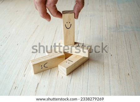 Wooden cubes depicting emotions scattered on the floor, with the happy face on top being choose by the person. Concept of emotional expression and positive vibes. Royalty-Free Stock Photo #2338279269