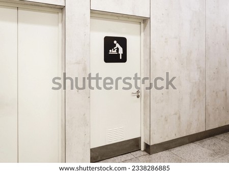 toilet doors for female genders in the airport with an icon of a person changing a baby's diapers on the diaper table. special separate room for mother and child. changing room