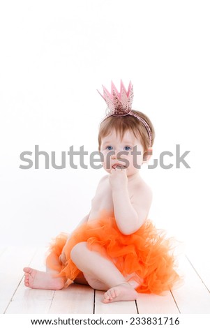 Picture of beautiful little princess girl with a mirror over white. An adorable baby girl sitting pretty in her pink and black princess costume. Isolated on white.