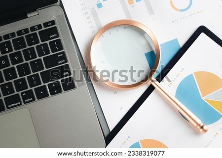 Business graphs, Magnifying glass placed on paper charts and laptop on table. Stock Market Analysis magnifier graphics business. Financial development, Banking Account, Statistics.