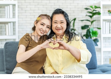 In truth, a family is what you make it. Shot of happy smiling asian senior mother and daughter making a heart sign with their hands at home, family enjoying leisure time