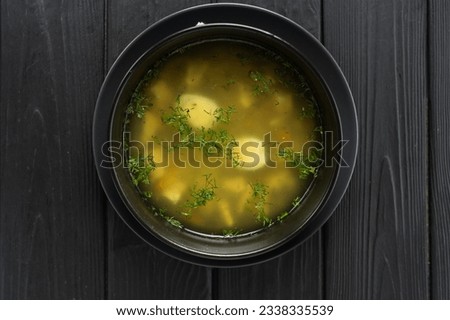 Chicken broth on a dark wooden background, top view, close-up, copy space