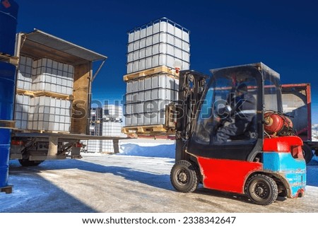 Logistics machines. Forklift is loading truck. Pallets with containers are being prepared for transportation. Territory of logistics center. Forklift with plastic tare in lathing. Shipping, delivery Royalty-Free Stock Photo #2338342647