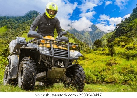 Man on ATV. Guy drives off-road. Four-wheel motorcycle driver. Quad biker in picturesque place. ATV for extreme recreation. Man in yellow helmet sits on quad bike. ATV with driver in sunny weather Royalty-Free Stock Photo #2338343417