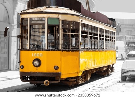 Historic tram or streetcar in the city centre of Milan in Italy. Single old timer car for public transport passing the cathedral and opera in midtown. Blurred black and white vintage background.  Royalty-Free Stock Photo #2338359671