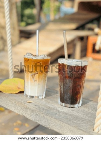 A cup of coffee on wooden swing under tree with a wooden house blurred background. Coffee time, Relaxing
