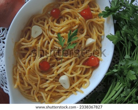 Top view of spaghetti noodles prepared with pepper and garlic with green parsley leaves