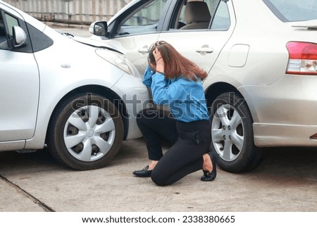 Stressed Asian woman holding her head sitting on the road Look at the cars that were hit. Transportation concept. car accident insurance Royalty-Free Stock Photo #2338380665
