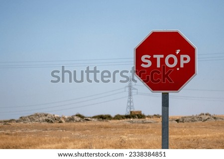 Stop sign, which has been shot with a firearm, in the background you can see cables and an electric tower. Concept: prohibited, demand power station Royalty-Free Stock Photo #2338384851
