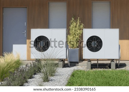 A pair of air source heat pumps, an eco-friendly home heating solution, installed at a contemporary residential property. Royalty-Free Stock Photo #2338390165
