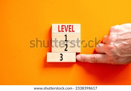 Time to level 3 symbol. Concept word Level 1 2 3 on wooden block. Businessman hand. Beautiful orange table orange background. Business planning and time to level 3 concept. Copy space.