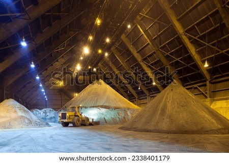 Mechanical shovel arranging copper concentrate stock pile. Royalty-Free Stock Photo #2338401179