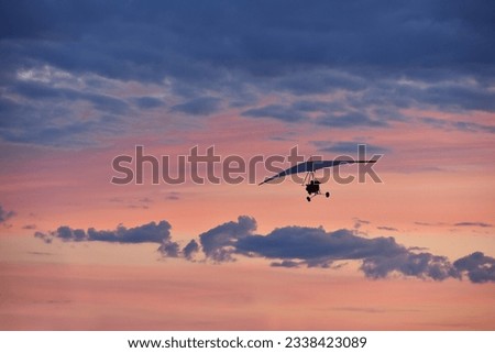 Hang glider on a motor on a summer evening against the backdrop of a sunset sky. Extreme sport. Banner, blank for an advertising layout with a place for writing