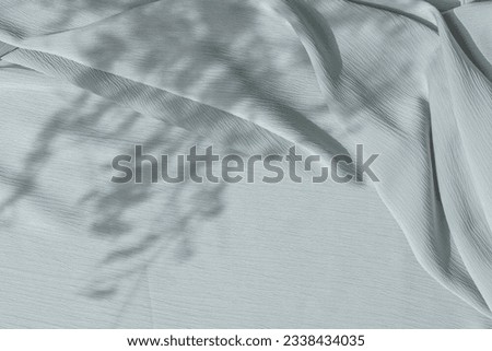 Light blue fabric texture with folds and natural floral sunlight shadows. Aesthetic summer wedding bohemian background