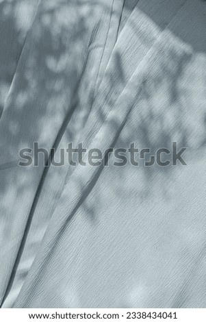 Aesthetic natural textile background with abstract sunlight shadow. Neutral light blue draped fabric, copy space