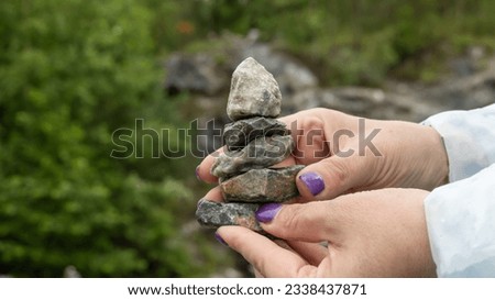 The woman's hands balance the stones stacked on top of each other in the form of a pyramid. Background picture.