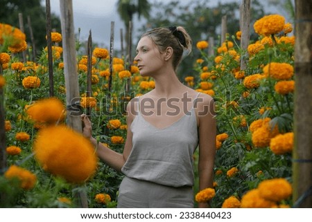 Portrait of  Caucasian tourist woman in field of Marigold Tagetes in bloom in Island of Bali