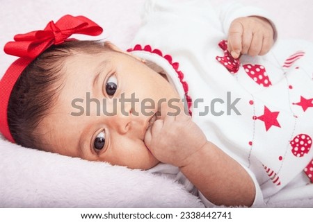 Close up of a sweet one month baby girl wearing a red and white christmas tshirt.