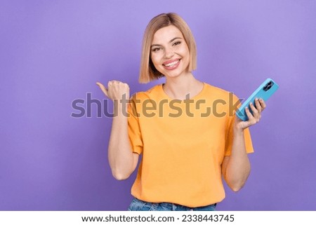 Portrait of optimistic girl dressed stylish clothes indicating at discount empty space hold smartphone isolated on violet color background