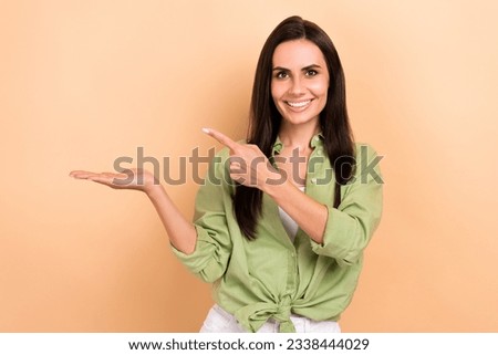 Portrait of nice cheerful girl toothy smile direct finger arm hold presenting empty space news isolated on beige color background