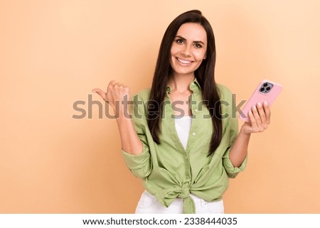 Portrait of positive pretty person hold apple iphone gadget direct finger empty space ad isolated on beige color background