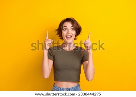 Portrait of astonished impressed ecstatic woman wear khaki top indicating at big sale empty space isolated on yellow color background Royalty-Free Stock Photo #2338444295
