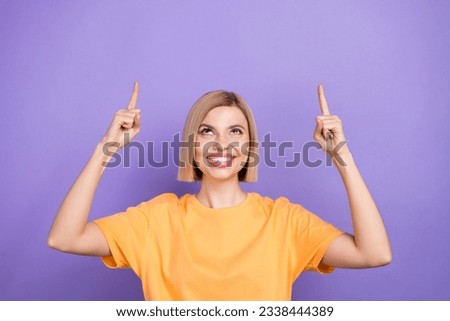 Portrait of beautiful curious girl direct fingers up empty space showing adv promo tips wear t-shirt isolated purple color background