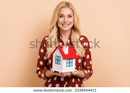 Photo of stunning positive person toothy smile arms hold showing little house isolated on beige color background